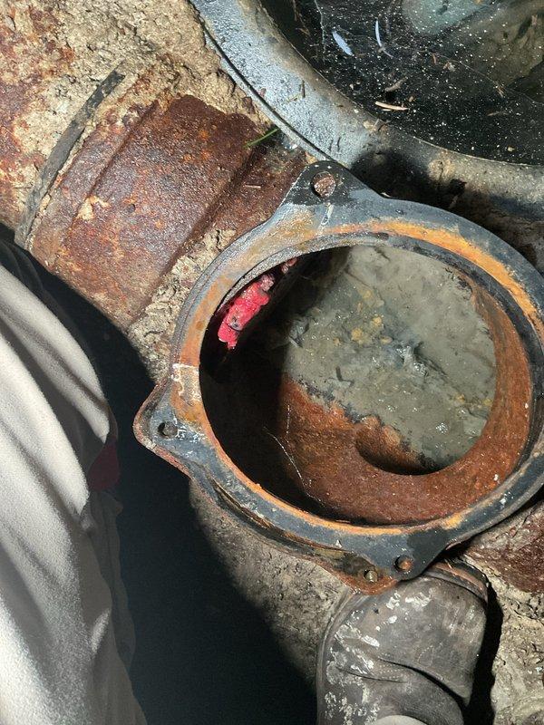 Performed annual maintenance on existing sewer backup system in century-old residence, confirming proper operation of all components. Conducted camera inspection of main sewer line from backup system to street connection to assess condition and check for root intrusion. Inspection revealed severely corroded metal piping with extensive rust deterioration, flaking, and pitting throughout the fitting assembly, indicating advanced age and moisture exposure. Accessed main line through exterior cleanout, documenting pipe condition with photographic evidence showing compromised structural integrity of metal components and potential failure points requiring future attention.