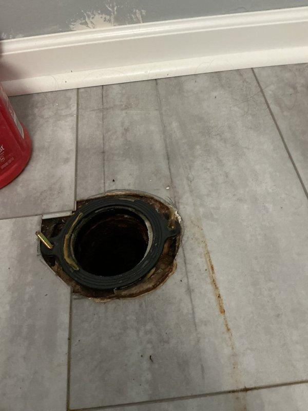 Investigated water leak reported above finished basement ceiling and traced source to failed toilet wax ring seal on upper level bathroom. Removed toilet to access flange assembly, which showed significant deterioration, rust staining, and water damage to surrounding floor tiles. Replaced defective wax ring seal, reinstalled toilet with proper sealing, and verified no active leaks during testing.