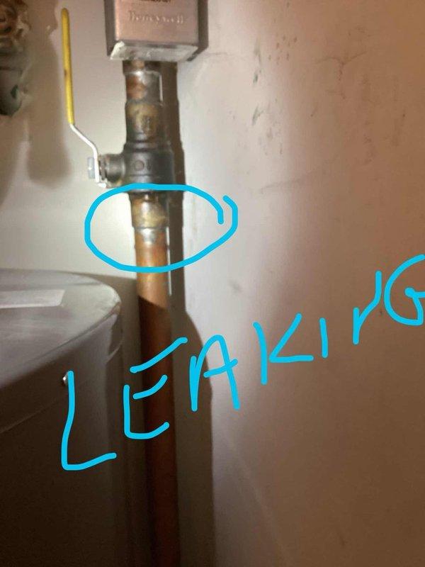 Responded to water leak complaint near tank area. Upon inspection, located active leak on vertical copper supply line and identified significant corrosion at pipe junction point with mounting bracket. Documented corroded connections displaying greenish-blue patina and rust-colored staining, indicating prolonged moisture exposure and deterioration of plumbing infrastructure.