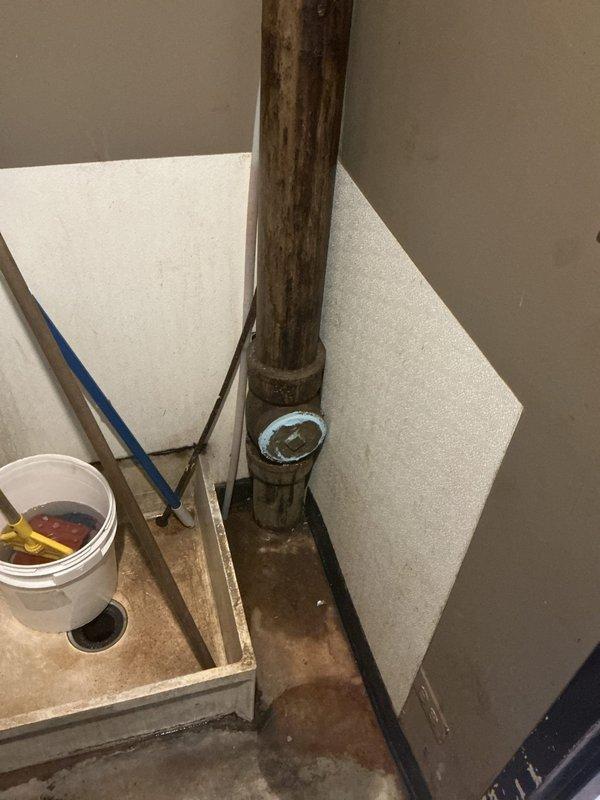 Conducted comprehensive drain and sewer system assessment at commercial facility, documenting conditions of underground infrastructure and building plumbing components. Inspection revealed severely corroded vertical cast iron waste stack in basement utility area with advanced oxidation requiring attention, along with evaluation of exterior loading dock area including underground sewer access points and drainage systems serving the warehouse operations.