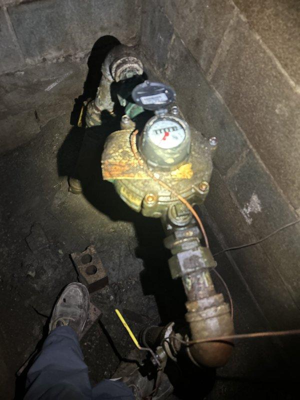 Conducted initial site assessment for commercial tankless water heater installation. Documented existing plumbing infrastructure, including heavily corroded copper piping with extensive yellow-green oxidation and mineral buildup at water meter assembly and vertical supply lines. Installation requires return visit to complete tankless water heater system commissioning.