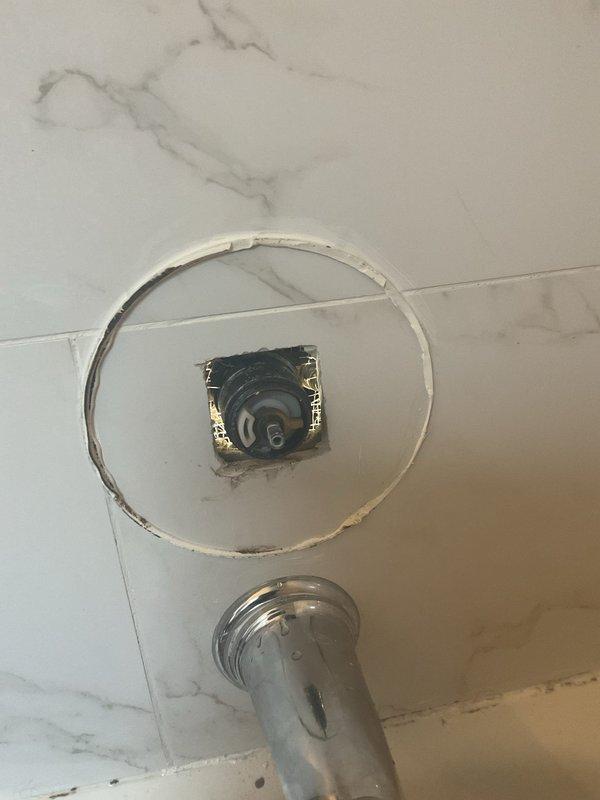 Responded to callback for ongoing leak in shower area. Upon arrival, performed pressure testing of shower valve assembly using diagnostic gauges to identify source of continued water intrusion. Inspected wall-mounted shower arm connection and escutcheon plate where previous repair work had been completed. Documented existing conditions including residual mounting marks and access panel to valve body. Testing revealed persistent leak requiring further investigation of internal valve components or supply line connections behind wall access point.