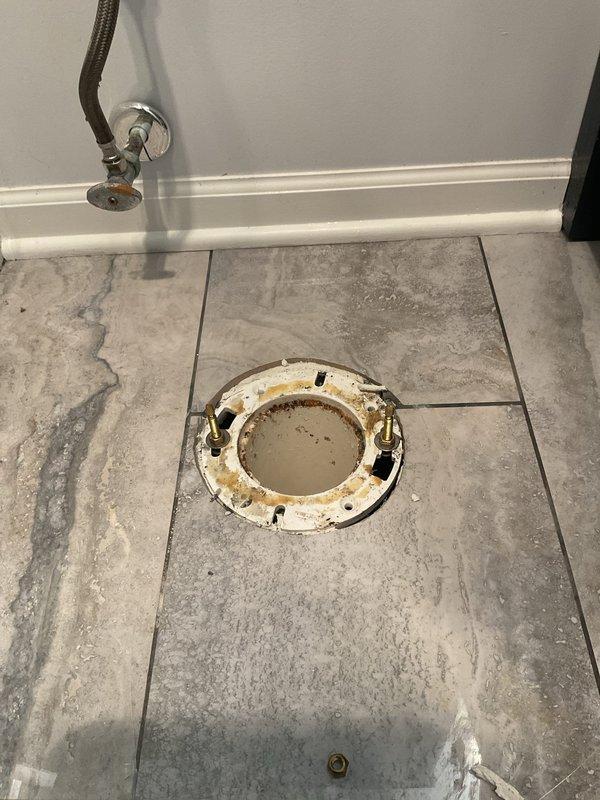 Responded to a service call for a toilet leaking at the base. Upon inspection, discovered a heavily corroded and deteriorated toilet flange with significant rust damage and water staining. Removed the existing toilet to access the damaged flange and assess the subfloor condition. The flange showed extensive corrosion around the mounting holes and inner ring, indicating prolonged moisture exposure. Inspected the underlying plumbing system, including PVC drain lines and structural support beneath the bathroom floor. Documented the condition of the corroded flange and plumbing infrastructure for repair recommendations.