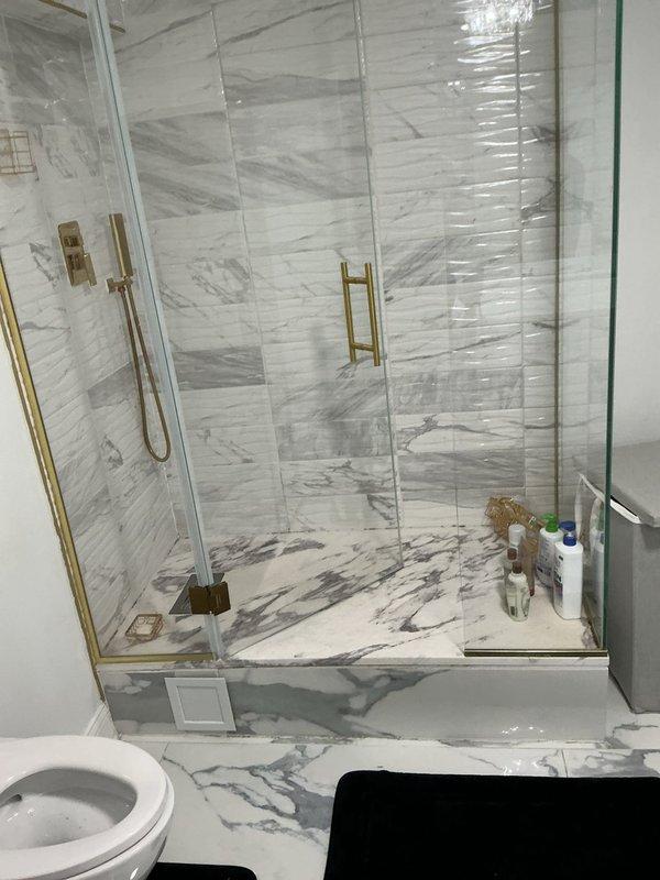 Responded to service call at 50-year-old residence for shower leak and low water pressure in toilet. Upon inspection of the bathroom with marble tile surround and gold-toned fixtures, identified source of shower leak at valve connections and addressed water flow restriction affecting toilet fill valve. Repaired shower plumbing connections, replaced worn washers, and adjusted toilet fill valve to restore proper water pressure. Tested all fixtures to confirm leak resolution and adequate flow restoration. System operating normally upon completion.