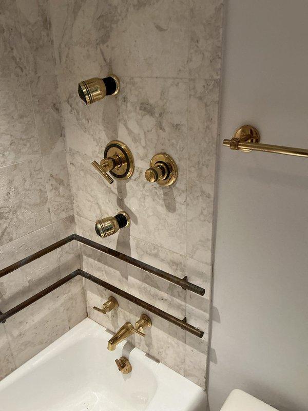 Responded to service call at 50-year-old residence for shower leak and low water pressure in toilet. Upon inspection of the bathroom with marble tile surround and gold-toned fixtures, identified source of shower leak at valve connections and addressed water flow restriction affecting toilet fill valve. Repaired shower plumbing connections, replaced worn washers, and adjusted toilet fill valve to restore proper water pressure. Tested all fixtures to confirm leak resolution and adequate flow restoration. System operating normally upon completion.