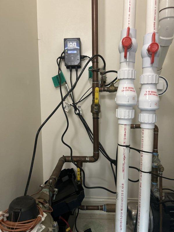 Performed warranty service on residential hydronic heating circulation system. Inspected and verified operation of circulation pump, digital control unit, and associated piping assembly including white PVC supply lines, ball valve shut-offs, and threaded unions. Confirmed proper function of pump mounted in protective housing, checked electrical connections and control wiring, and documented system configuration with red-handled isolation valves in serviceable condition for future maintenance access.
