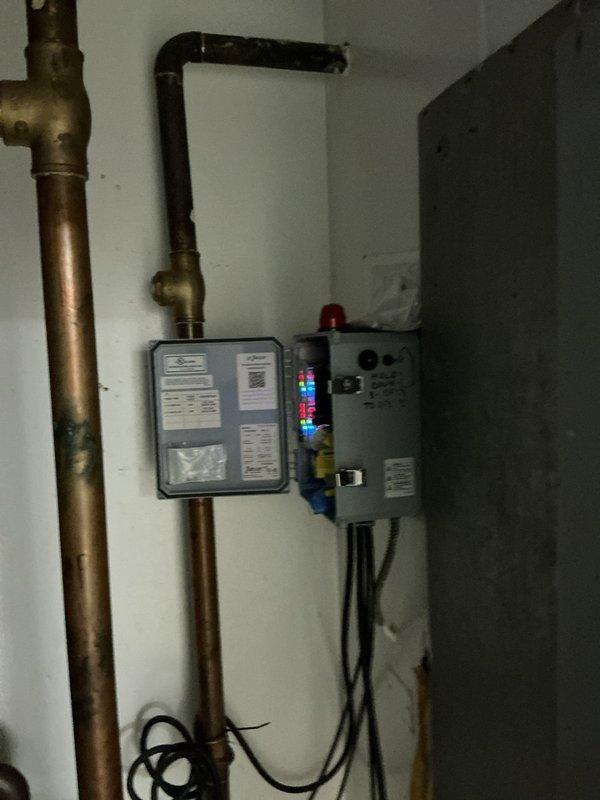 Responded to service call for sump pump alarm indicating basin filled to capacity. Upon arrival, discovered severely corroded water heater with extensive rust damage and structural deterioration requiring immediate replacement rather than sump pump issue as initially reported. Documented existing conditions showing compromised tank integrity with oxidation penetration throughout metal casing. Observed mechanical room setup with copper supply lines, electrical connections, and control panel requiring coordination for new installation. Assessed utility room layout including tile flooring, drainage access, and clearance requirements for equipment replacement to ensure code compliance and proper functionality of new system.