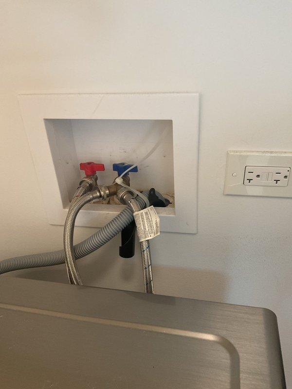 Responded to water leak in second floor laundry room that was dripping through ceiling into first floor light fixture. Upon arrival, inspected washing machine supply connections and identified source of leak at water supply valve connections. Tightened braided stainless steel flex supply lines at both hot and cold water shutoff valves to eliminate leak. Verified leak had stopped and no water was actively dripping. Inspected first floor ceiling and light fixture below for water damage; confirmed no significant damage observed. Cycled washing machine through fill cycle to test connections under pressure and verified repair was successful with no additional leakage detected. Photographed completed work showing properly secured supply connections and surrounding area.