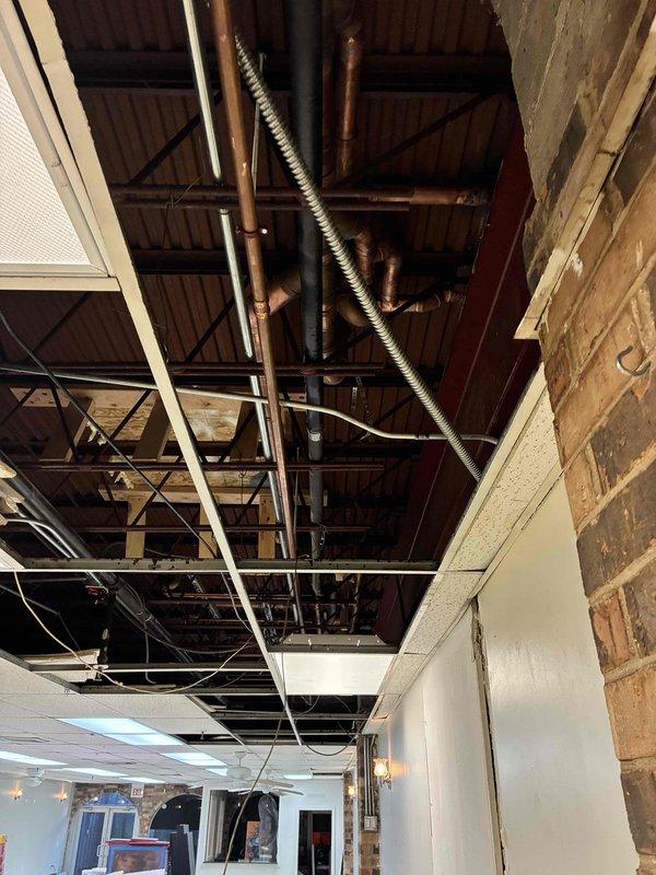Completed installation of copper piping system in commercial space with exposed ceiling infrastructure. Installed vertical pipe runs with proper valve fittings and integrated new plumbing lines with existing mechanical systems including ductwork and electrical conduits. Parts were provided for the installation, and comprehensive documentation photos were captured showing the completed work in the exposed ceiling area and floor-level valve installations.
