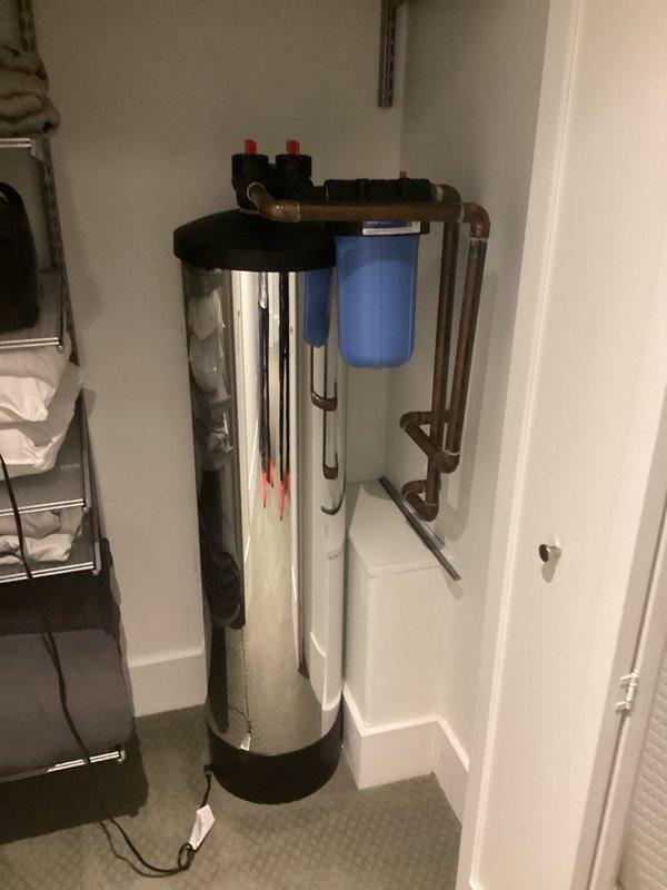Completed installation of whole-house water filtration system including a stainless steel treatment tank with dual pressure relief valves and blue sediment filter housing with integrated copper piping. Additionally performed maintenance flush on the tankless water heater as requested to remove mineral buildup and ensure optimal performance.