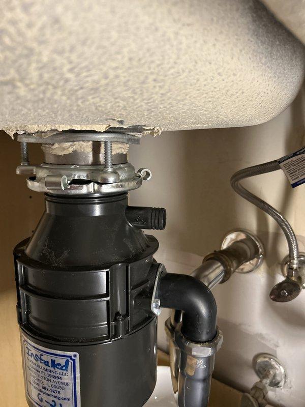 Completed warranty service call for kitchen sink water line inspection. Upon arrival, performed comprehensive assessment of under-sink plumbing system including garbage disposal unit, P-trap assembly, and water supply connections. All components found to be properly installed and functioning correctly with no visible leaks, corrosion, or damage detected. Chrome-plated drain assembly and braided metal supply lines confirmed secure with intact connections. Documented existing conditions with photographic evidence showing disposal mounting assembly, PVC drainage piping, shut-off valve, and dishwasher connection all in satisfactory working order.