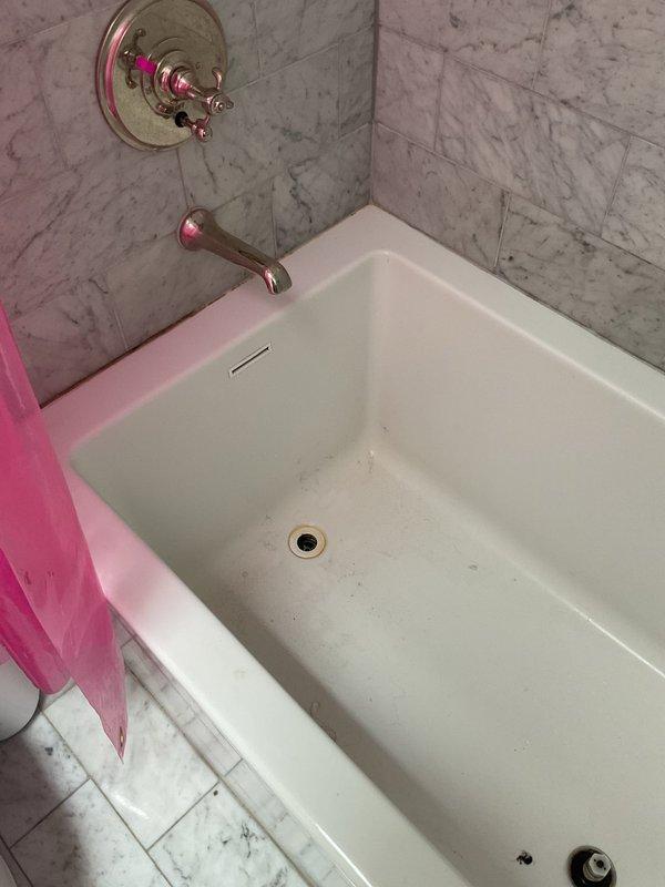 Responded to clogged drain call at residential property constructed in 1888. Upon arrival, assessed bathroom fixtures including bathtub with chrome faucet assembly and TOTO toilet. Identified slow drainage issue affecting bathtub drain. Utilized drain snake to clear obstruction from drain line, removing accumulated hair and soap residue buildup common in older plumbing systems. Tested water flow post-clearing to confirm proper drainage restored. Inspected visible plumbing connections and fixtures for any additional concerns related to the age of the home's infrastructure. All fixtures functioning properly upon service completion.