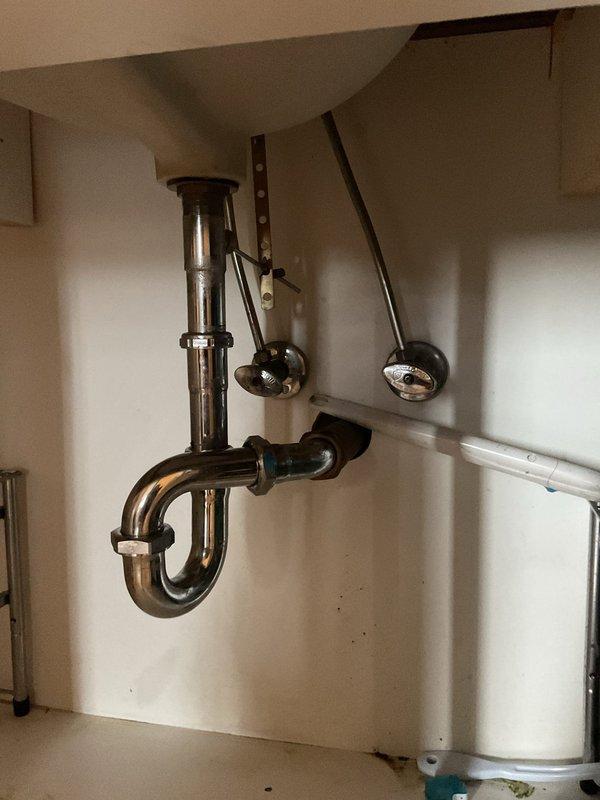 Responded to service call for bathroom sink drainage issue and dripping pop-up drain assembly. Upon inspection, found the P-trap and tailpiece assembly under the Kohler undermount sink required attention. Disassembled the chrome-plated P-trap configuration, cleared obstruction from drain line, and inspected all connections for proper sealing. Reinstalled P-trap assembly, verified wall-mounted securing brackets were properly fastened, and tested pop-up drain mechanism for proper operation and seal. Ran water through system to confirm restored drainage flow and eliminate dripping issue at drain stopper assembly.