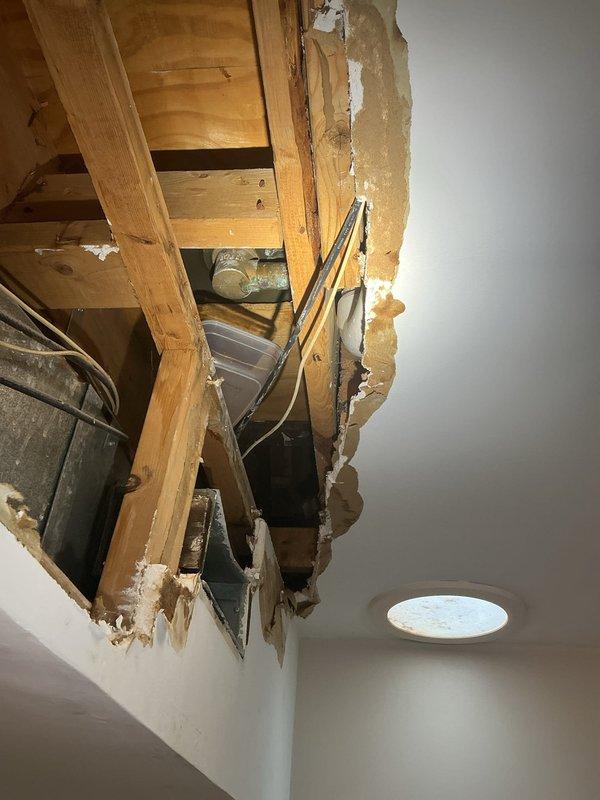 Responded to water leak in century-old residential property requiring emergency access through ceiling to locate source. Created access opening to expose plumbing infrastructure, wooden joists, and supply lines running through ceiling cavity. Identified leak origin, performed necessary repairs to affected piping, and documented existing conditions including ceiling damage and exposed structural components for restoration planning.