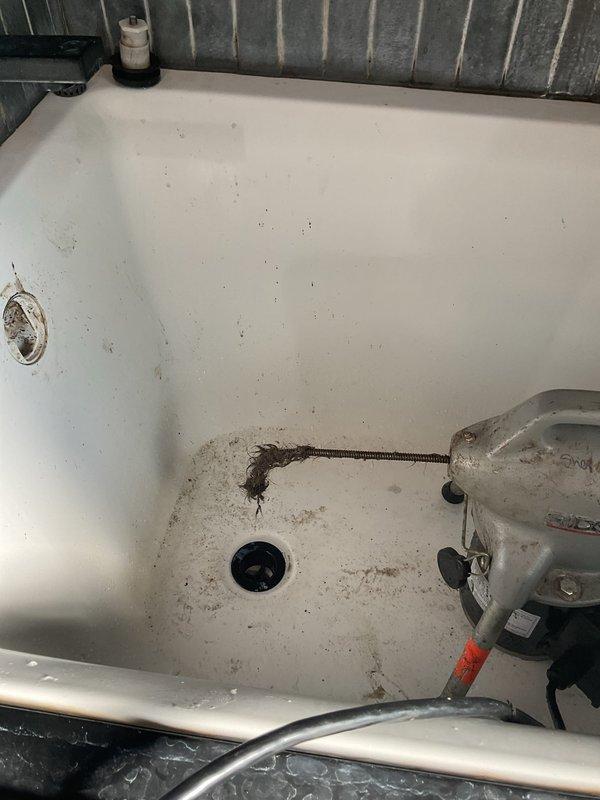 Responded to emergency service call for clogged shower drain in 1950s-era home. Upon arrival, found bathtub with significant drainage blockage preventing water flow. Deployed professional drain auger with flexible cable to access and clear the obstruction through the existing drain assembly. Successfully removed accumulated debris, hair, and soap buildup causing the blockage. Tested drainage flow to confirm full restoration of proper function. Left work area clean and operational.
