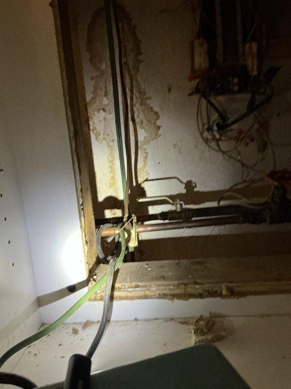 Responded to water leak complaint in 99-year-old residential property. Upon inspection, identified refrigerator supply line as primary source of leak affecting surrounding floor area. Accessed crawlspace and utility areas to assess extent of water damage to flooring and substructure. Inspected copper piping system throughout affected zone, checking for additional compromise due to age of plumbing infrastructure. Secured leaking refrigerator water supply line and verified all connections. Documented conditions of exposed piping, electrical systems, and structural components in utility spaces for homeowner records. Confirmed leak source isolated and water flow controlled.