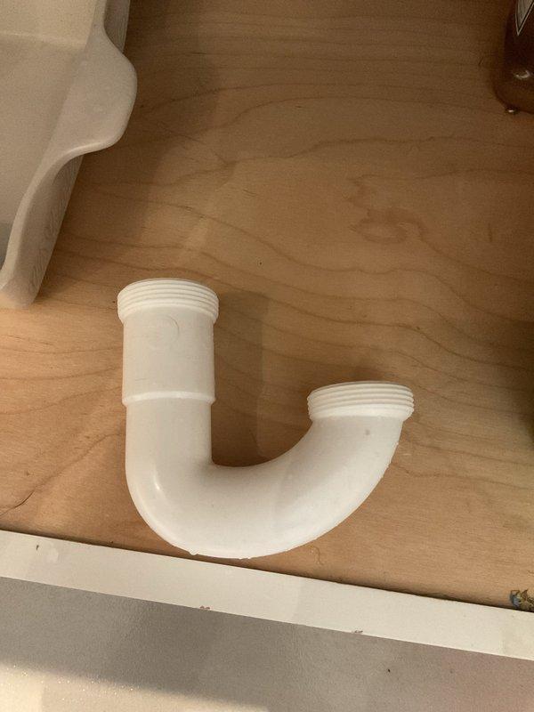 # Plumbing Service - Kitchen Sink Drain Repair

Responded to recurring failure of kitchen sink drain P-trap assembly in century-old residential property. Upon arrival, found white PVC P-trap pipe had separated from drain assembly beneath kitchen sink, marking second failure at this location within approximately one month of previous repair attempt by another service provider.

Inspection revealed the existing P-trap connections had failed due to inadequate threading engagement and potential stress from the garbage disposal unit weight distribution. Removed compromised P-trap assembly from under-sink cabinet. Assessed all threaded connections, drain tailpiece, and wall stub-out for damage or wear consistent with the property's age.

Installed new white PVC P-trap assembly with proper thread engagement at all connection points. Ensured correct alignment between garbage disposal outlet, drain tailpiece, and wall drain to prevent future stress on threaded fittings. Verified all slip-joint 
