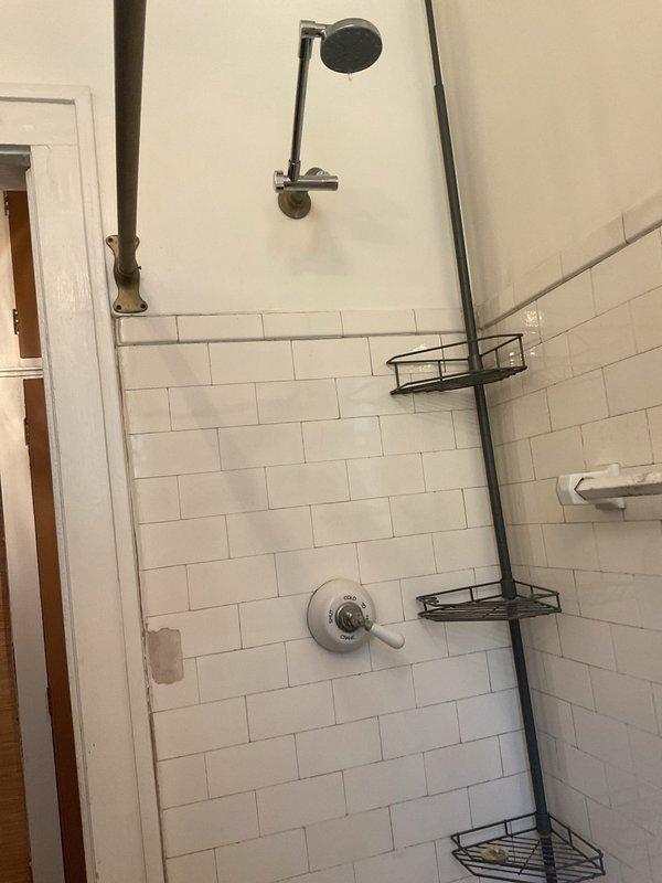Responded to service call for leaking shower faucet that customer was unable to repair by tightening. Inspected three-handle shower valve assembly with chrome fixtures mounted on subway tile wall above bathtub. Assessed condition of valve stems, packing, and trim components. Documented existing rust staining around tub drain and mineral deposits on fixtures indicating long-term water quality issues. Photographed shower plumbing system and overall bathroom condition for estimate preparation.