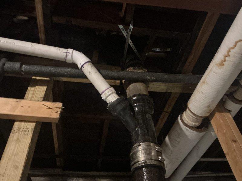 # Drain and Sewer Estimate Commercial

Conducted a comprehensive drain and sewer system assessment in an unfinished commercial basement space with exposed framing. Evaluated existing plumbing infrastructure including vertical black cast iron or ABS drainage lines, horizontal white PVC piping with purple reclaimed water markings, and insulated pipe sections. Documented the condition of pipe connections, couplings, and support systems within the wooden joist framework to provide accurate estimate for drainage system modifications or repairs.
