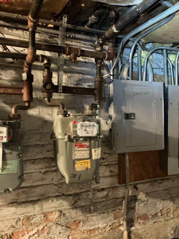 Responded to service call for reported gas leak at stove valve with appliances shut off. Performed visual inspection of gas system including meter, distribution piping, and appliance connections in basement utility area. Located leak at stove valve connection and documented existing conditions with photographs showing gas meter installation, copper supply lines, and affected valve area. Recommended repair or replacement of faulty valve to restore safe gas service to cooking appliance.