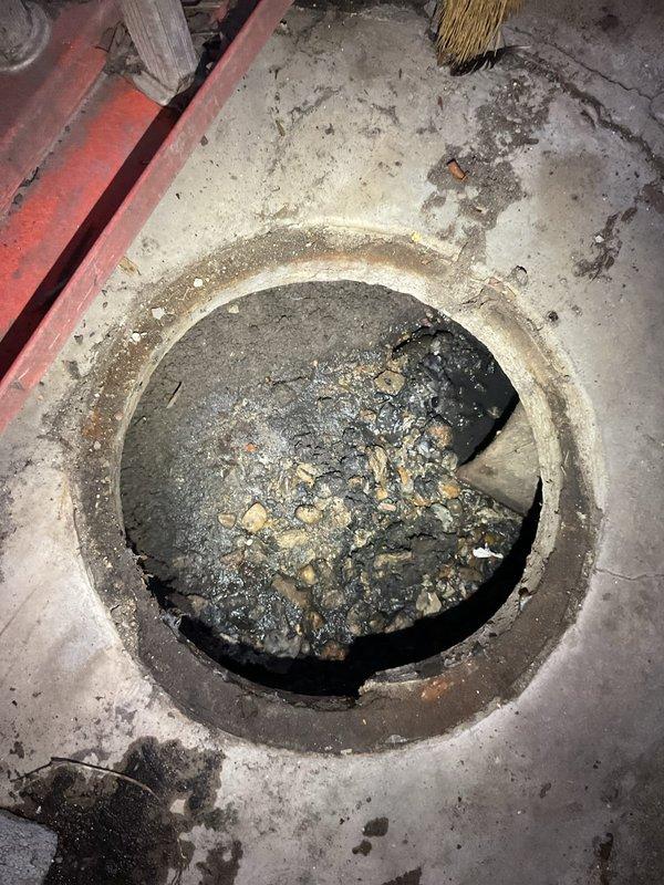 Responded to clogged toilet issue and conducted thorough diagnostic inspection of plumbing system. Upon investigation, discovered the problem extended beyond the fixture itself, identifying significant sediment accumulation in floor drain and severely discolored water in toilet tank indicating rust contamination or corroded supply line components. Documented conditions with photographic evidence showing debris-filled floor drain access port and brown-tinted water throughout tank assembly with worn flapper valve, suggesting deeper systemic plumbing concerns requiring further repair estimates.