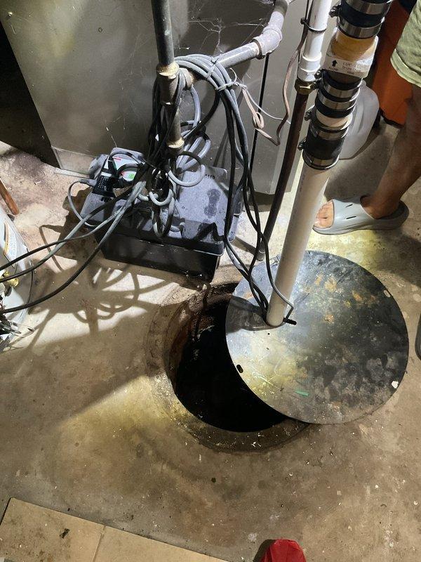 Replaced submersible sump pump in basement utility area. Removed old unit from sump pit, installed new black submersible pump with discharge piping connected to existing PVC drainage system, secured all electrical connections and cable management, and tested system for proper operation.