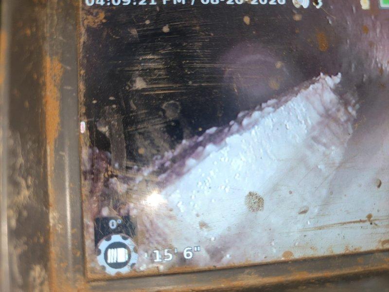 Responded to service call for beeping battery backup unit on sump pump system. Performed VIP maintenance on sump pump tank, inspecting all components and ensuring proper operation. Conducted camera inspection of outside cleanout, which revealed significant accumulation of white fibrous material, likely tree roots or mineral buildup, at approximately 15 feet 6 inches into the line. Documentation captured shows extensive blockage requiring attention and weathered pipe conditions with visible corrosion and debris throughout the inspected section.