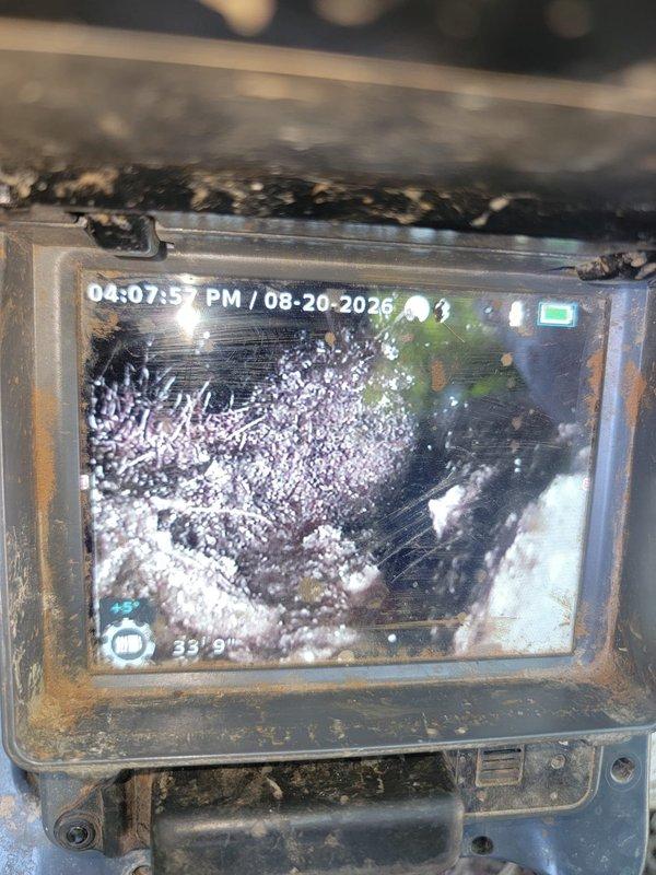 Responded to service call for beeping battery backup unit on sump pump system. Performed VIP maintenance on sump pump tank, inspecting all components and ensuring proper operation. Conducted camera inspection of outside cleanout, which revealed significant accumulation of white fibrous material, likely tree roots or mineral buildup, at approximately 15 feet 6 inches into the line. Documentation captured shows extensive blockage requiring attention and weathered pipe conditions with visible corrosion and debris throughout the inspected section.