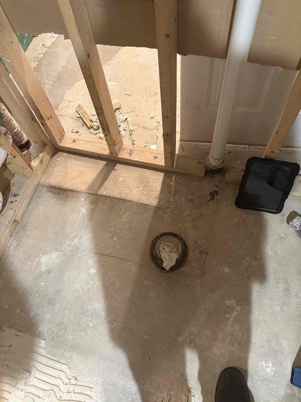 Provided comprehensive plumbing estimate for remodel project involving drainage system installation in older building with exposed brick walls. Assessment included evaluation of existing floor drain, new PVC waste line routing through wall cavities, and integration with structural framing requirements. Documented current conditions of concrete flooring, drain pan placement, and vertical pipe runs to support detailed piping scope for renovation work.
