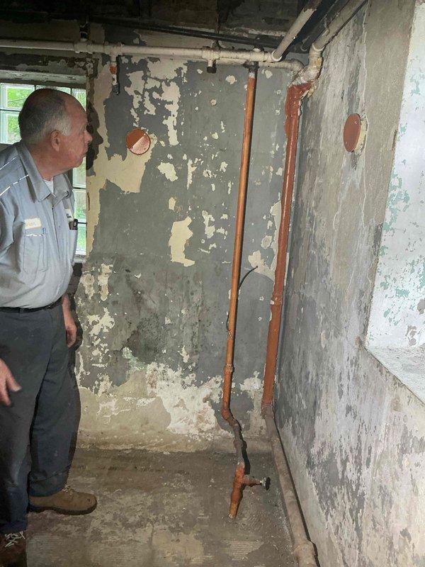 Conducted comprehensive plumbing assessment of basement area exhibiting severe water damage and deteriorated conditions. Evaluated multiple copper supply lines showing significant oxidation and corrosion running vertically along damaged walls. Documented extensive structural deterioration including peeling paint layers, exposed substrate, and moisture-related damage throughout the space. Identified aging plumbing infrastructure requiring repair or replacement and provided recommendations for remediation of affected piping systems and water-damaged surfaces.