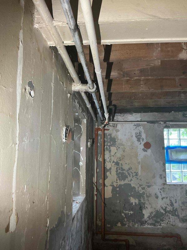 Conducted comprehensive plumbing assessment of basement area exhibiting severe water damage and deteriorated conditions. Evaluated multiple copper supply lines showing significant oxidation and corrosion running vertically along damaged walls. Documented extensive structural deterioration including peeling paint layers, exposed substrate, and moisture-related damage throughout the space. Identified aging plumbing infrastructure requiring repair or replacement and provided recommendations for remediation of affected piping systems and water-damaged surfaces.