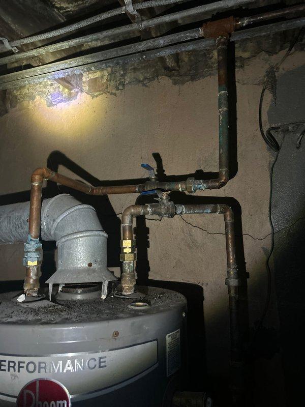 Conducted comprehensive plumbing assessment of century-old residential property to provide estimate for complete repiping of bathroom and additional areas. Evaluated existing lead and galvanized water supply lines throughout the structure, documenting deteriorated piping systems requiring replacement with copper piping to meet current code requirements. Inspected bathroom plumbing infrastructure including vertical pipe stacks experiencing active leak conditions. Assessed under-sink drainage system with PVC P-trap configuration and examined water heater installation with aged copper supply lines showing significant oxidation and patina. Documented existing plumbing conditions through photographic evidence including cabinet-mounted fixtures, supply line routing, and mechanical room infrastructure. Evaluated scope of work necessary to bring entire plumbing system into code compliance, focusing on bathroom stack replacement and transition from obsolete materials to modern copper distributi