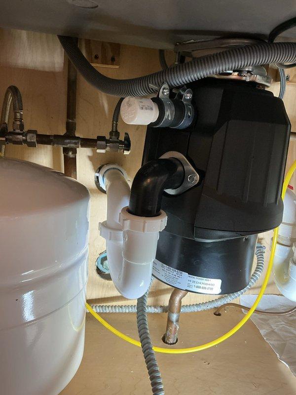 Performed plumbing repair service on bathroom and kitchen sink installations. Inspected and serviced chrome P-trap assembly beneath bathroom sink, utilizing pipe wrench to ensure proper connections and seal integrity. Verified kitchen sink plumbing system including garbage disposal unit, white P-trap assembly, water supply lines with shut-off valves, and integrated water filtration canister. All components confirmed to be properly secured and functioning correctly upon completion of service.