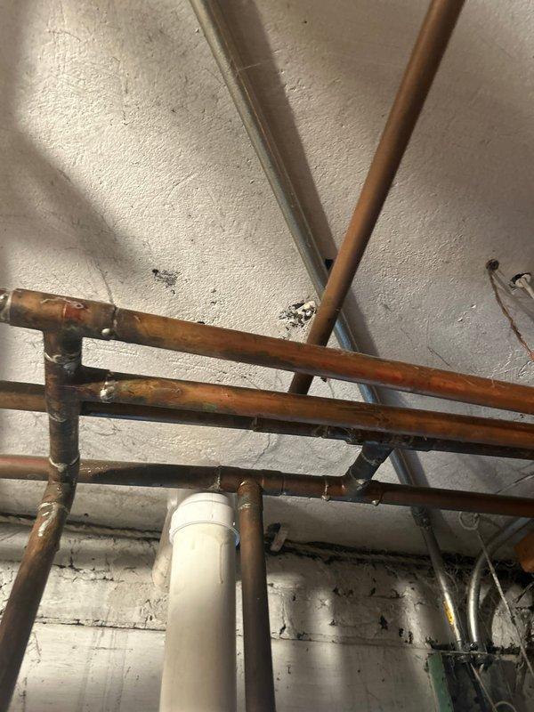 Conducted on-site assessment for water heater replacement in century-old residential property. Evaluated existing plumbing infrastructure including aged copper supply lines, distribution piping, and venting requirements for installation of 50-gallon power vent water heater unit. Documented current mechanical room conditions, existing pipe configurations with oxidized copper piping, PVC venting system, and available clearances for new equipment installation in basement utility area.