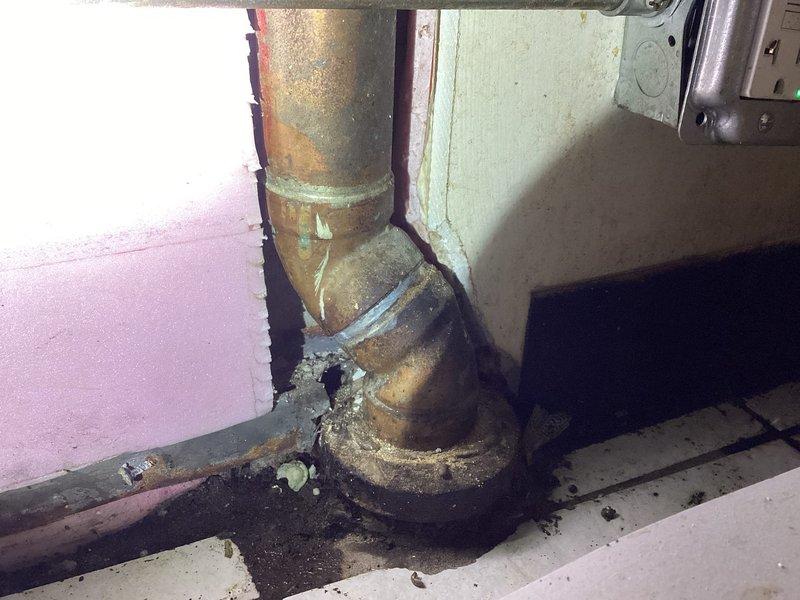 Completed plumbing estimate for severely corroded pipe assembly under kitchen sink, including vertical supply line and elbow joint connection at floor level. Documented extensive rust deterioration, surface flaking, and oxidation damage throughout the piping system, with particular corrosion concentration at the elbow joint and lower pipe sections. Photographed conditions and provided repair quote for replacement of affected piping components.