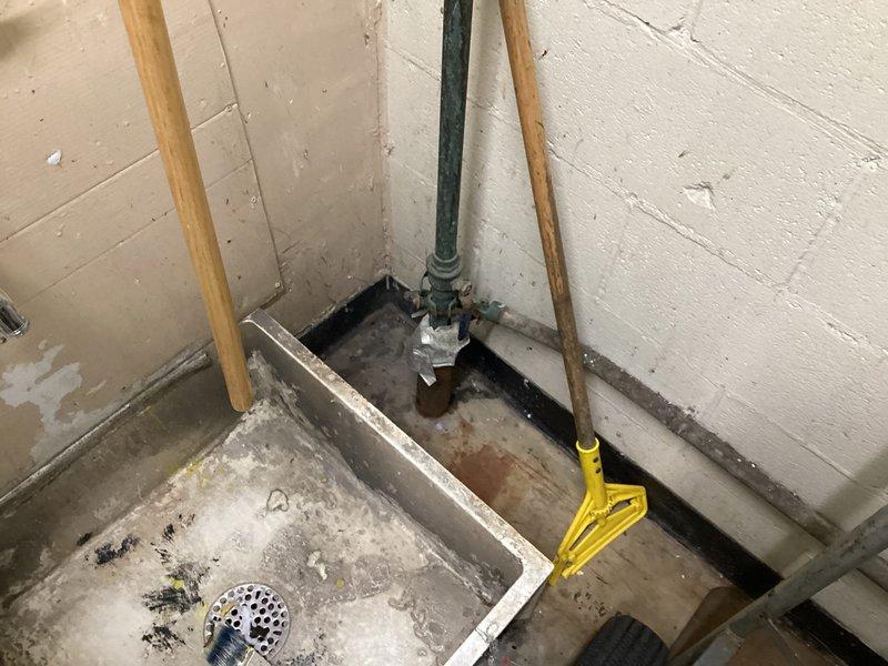 Completed plumbing estimate for severely corroded pipe assembly under kitchen sink, including vertical supply line and elbow joint connection at floor level. Documented extensive rust deterioration, surface flaking, and oxidation damage throughout the piping system, with particular corrosion concentration at the elbow joint and lower pipe sections. Photographed conditions and provided repair quote for replacement of affected piping components.