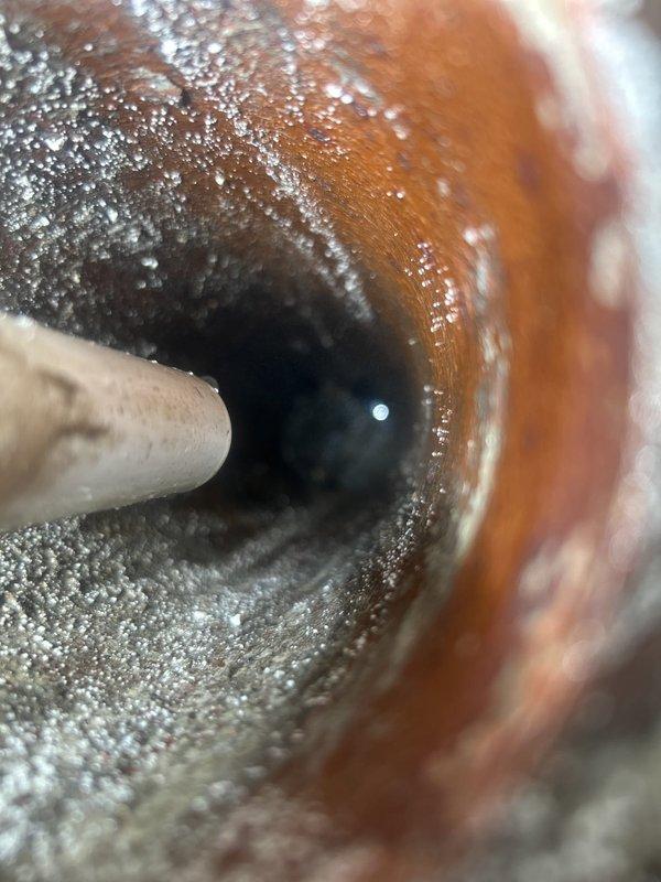 Responded to service call for clogged floor drain and water heater inspection. Upon arrival, assessed the floor drain condition and performed diagnostic evaluation of the water heater system. Inspection revealed significant mineral scale and crystalline buildup accumulation on copper piping connections, indicating long-term hard water deposits affecting water flow and system efficiency. Documented water heater unit specifications, safety labels, and current operational status with detailed photographic evidence. Provided assessment findings and recommendations for addressing mineral buildup issues and ensuring proper drainage system function.