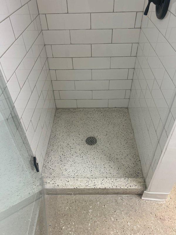 Performed camera inspection of residential plumbing system for newly installed shower stall with subway tile walls and terrazzo flooring. Documented drain system functionality and verified proper installation of central floor drain with chrome cover, as well as secondary floor drain location marked for future service work.