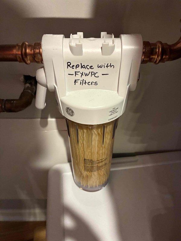 Responded to service call for water heater inspection and low water flow complaint at kitchen faucet. Upon arrival, performed comprehensive inspection of tanked water heater system, examining internal components including copper piping manifold, electrical connections, brass valves, and shutoff mechanisms. All connections, wiring, and heating elements were inspected for proper operation and safety compliance. Water heater found to be functioning within normal parameters with no immediate issues identified.

Investigated low water flow concern at kitchen faucet and traced issue to whole-house water filtration system installed on main copper supply line. Inspection revealed GE brand inline filter housing with severely discolored and clogged filter cartridge, exhibiting brownish-yellow sediment buildup that was significantly restricting water flow throughout the residence. Filter cartridge had reached end of service life and required immediate replacement. Documented existing filter model