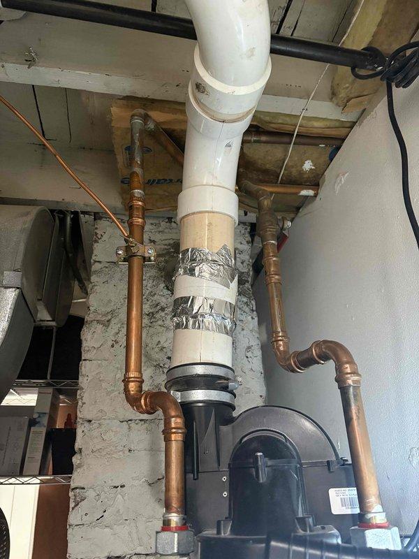 Completed annual VIP plumbing maintenance inspection of residential property. Inspected and documented basement plumbing infrastructure including main vertical PVC drain stack with aluminum foil tape wrapping secured by plastic straps, copper supply line T-junction connections with compression fittings, and circulation pump unit with rubber flexible connectors. Verified proper operation of kitchen sink garbage disposal system (InSinkErator unit) and under-sink water filtration canister with associated supply lines and shut-off valves. All components found operating within normal parameters with no leaks detected at time of inspection.