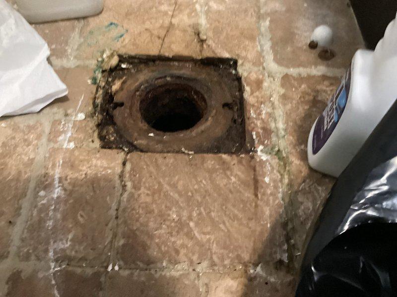 Responded to emergency plumbing call for toilet flange and pipe leaking through ceiling into unit below. Upon inspection, discovered severely corroded cast iron flange and deteriorated drain pipe beneath toilet. Documented extensive rust damage and structural compromise of existing flange assembly. Removed flooring material around affected area to assess full extent of corrosion and prepare access point for replacement work. Provided comprehensive quote for complete replacement of cast iron flange, drain pipe, and galvanized connections, with option for new toilet installation to prevent future leaks and ensure proper seal.