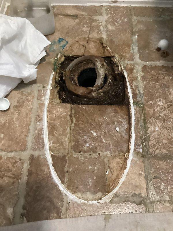 Responded to emergency plumbing call for toilet flange and pipe leaking through ceiling into unit below. Upon inspection, discovered severely corroded cast iron flange and deteriorated drain pipe beneath toilet. Documented extensive rust damage and structural compromise of existing flange assembly. Removed flooring material around affected area to assess full extent of corrosion and prepare access point for replacement work. Provided comprehensive quote for complete replacement of cast iron flange, drain pipe, and galvanized connections, with option for new toilet installation to prevent future leaks and ensure proper seal.