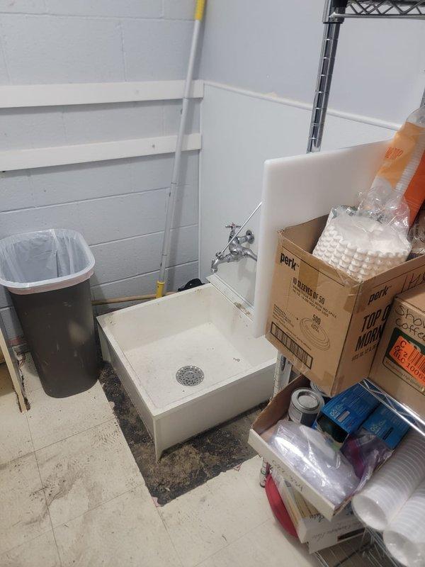 Responded to commercial property experiencing drainage backup in toilets and sinks during rain events. Inspected utility area plumbing system and main drainage lines to identify source of water intrusion causing fixture backups. Located and assessed floor-mounted mop sink, drainage infrastructure, and associated piping to determine blockage points and verify proper drainage flow throughout the system.