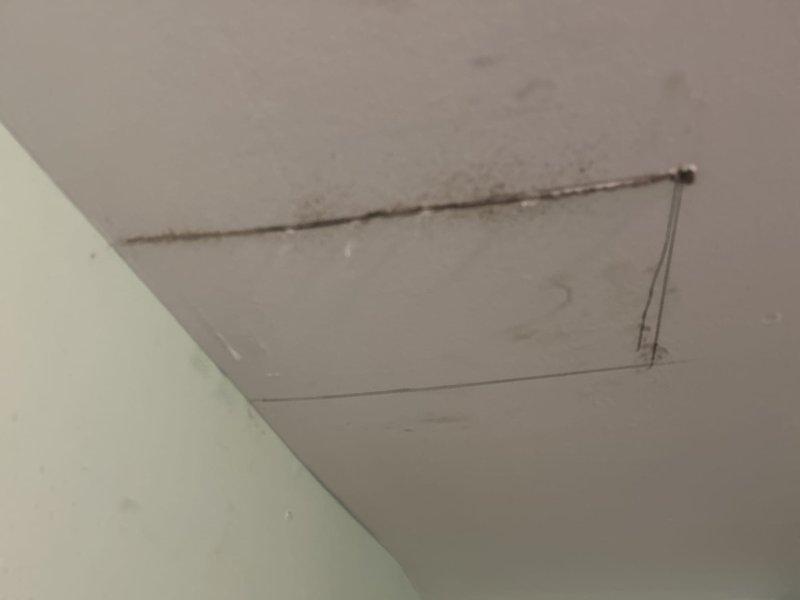 Responded to apartment water leak investigation request. Upon arrival, conducted thorough visual inspection of affected areas and identified active water intrusion evidenced by ceiling staining and discoloration with brownish-gray water marks concentrated around rectangular access panel area. Created exploratory opening in wall near ceiling junction to access concealed plumbing and structural components for source identification. Inspection revealed moisture damage to wooden framing members behind finished drywall surfaces. Documented conditions with photographic evidence showing extent of water damage to ceiling surfaces and exposed structural elements. Located leak source within concealed plumbing system accessible through investigation opening. Provided findings and recommendations for necessary repairs to address water intrusion and restore affected areas.