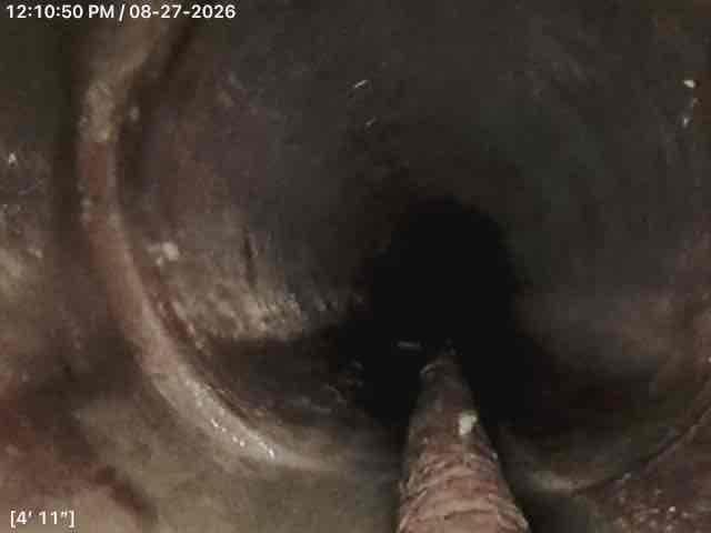 Performed comprehensive camera inspection of interior drain line system to assess condition and identify potential issues. Video inspection revealed significant deterioration and corrosion throughout the metal piping, with heavy buildup of debris and organic material accumulating on pipe walls. Camera documented conditions at multiple depths, capturing footage at 1'7" and 4'11" intervals showing progressive degradation of the system. Inspection identified areas of concern including corroded metal surfaces, accumulated grime, and potential structural compromise of the ductwork. Also completed pumping service for the basin as requested to ensure proper drainage function.