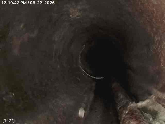Performed comprehensive camera inspection of interior drain line system to assess condition and identify potential issues. Video inspection revealed significant deterioration and corrosion throughout the metal piping, with heavy buildup of debris and organic material accumulating on pipe walls. Camera documented conditions at multiple depths, capturing footage at 1'7" and 4'11" intervals showing progressive degradation of the system. Inspection identified areas of concern including corroded metal surfaces, accumulated grime, and potential structural compromise of the ductwork. Also completed pumping service for the basin as requested to ensure proper drainage function.