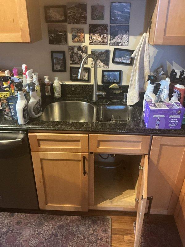 Conducted residential drain and sewer estimate for kitchen sink plumbing system. Assessed existing configuration including garbage disposal unit, P-trap assembly, and drainage piping beneath undermount sink installation. Documented current plumbing conditions and photographed cabinet interior showing disposal unit, PVC drainage connections, chrome P-trap, and dishwasher drain line routing for estimate preparation.