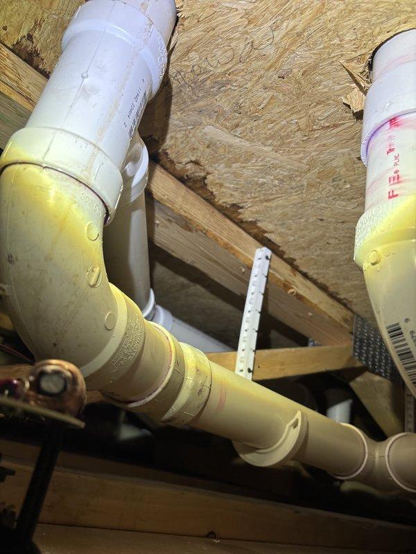 Responded to water leak service call and performed comprehensive plumbing inspection in residential bathroom and attic space. Located source of leak in drainage system within attic crawl space, where yellow PVC piping showed signs of moisture intrusion at connection points. Repaired compromised pipe joints and elbow fittings, ensuring proper seal and alignment of drainage lines. Verified all pipe hangers and mounting brackets were secure to wooden framing members. Inspected bathroom plumbing fixtures including walk-in shower enclosure, toilet, and vanity sink to confirm no additional leak sources or water damage present. All fixtures tested and confirmed operational with no active leaks detected upon completion.