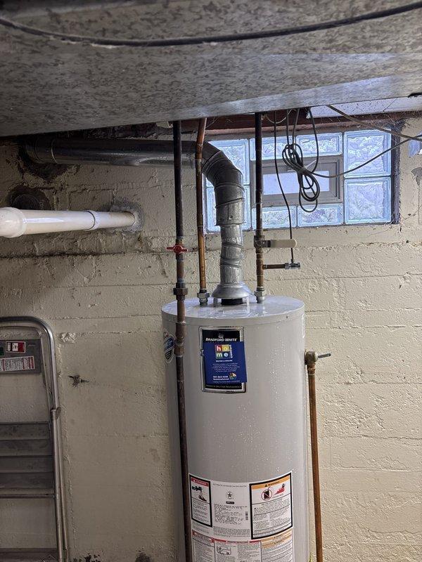 Responded to emergency service call for leaking gas water heater in residential basement. Upon inspection, identified Bradford White gas water heater with active leak requiring immediate replacement. Assessed existing plumbing configuration including copper supply lines, galvanized piping, metallic exhaust vent system, and connections to building's water supply. Provided detailed estimate for same-day water heater replacement, including removal of failed unit, installation of new gas water heater with proper venting, reconnection of all supply and discharge lines, and testing of safety controls and pressure relief systems.