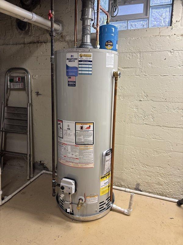 Responded to emergency service call for leaking gas water heater in residential basement. Upon inspection, identified Bradford White gas water heater with active leak requiring immediate replacement. Assessed existing plumbing configuration including copper supply lines, galvanized piping, metallic exhaust vent system, and connections to building's water supply. Provided detailed estimate for same-day water heater replacement, including removal of failed unit, installation of new gas water heater with proper venting, reconnection of all supply and discharge lines, and testing of safety controls and pressure relief systems.